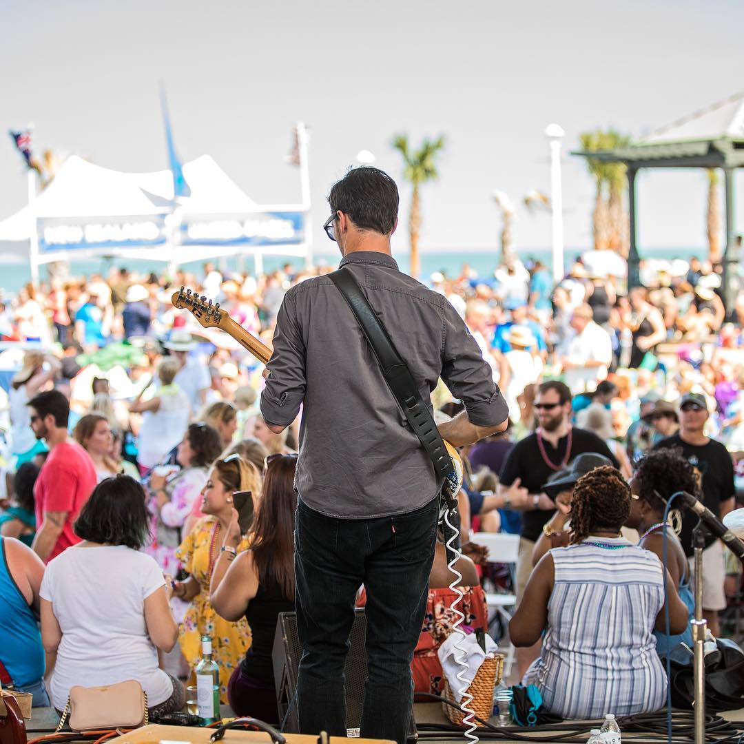 Guy standing on stage playing guitar at festival. Photo by Instagram user @neptunefestival