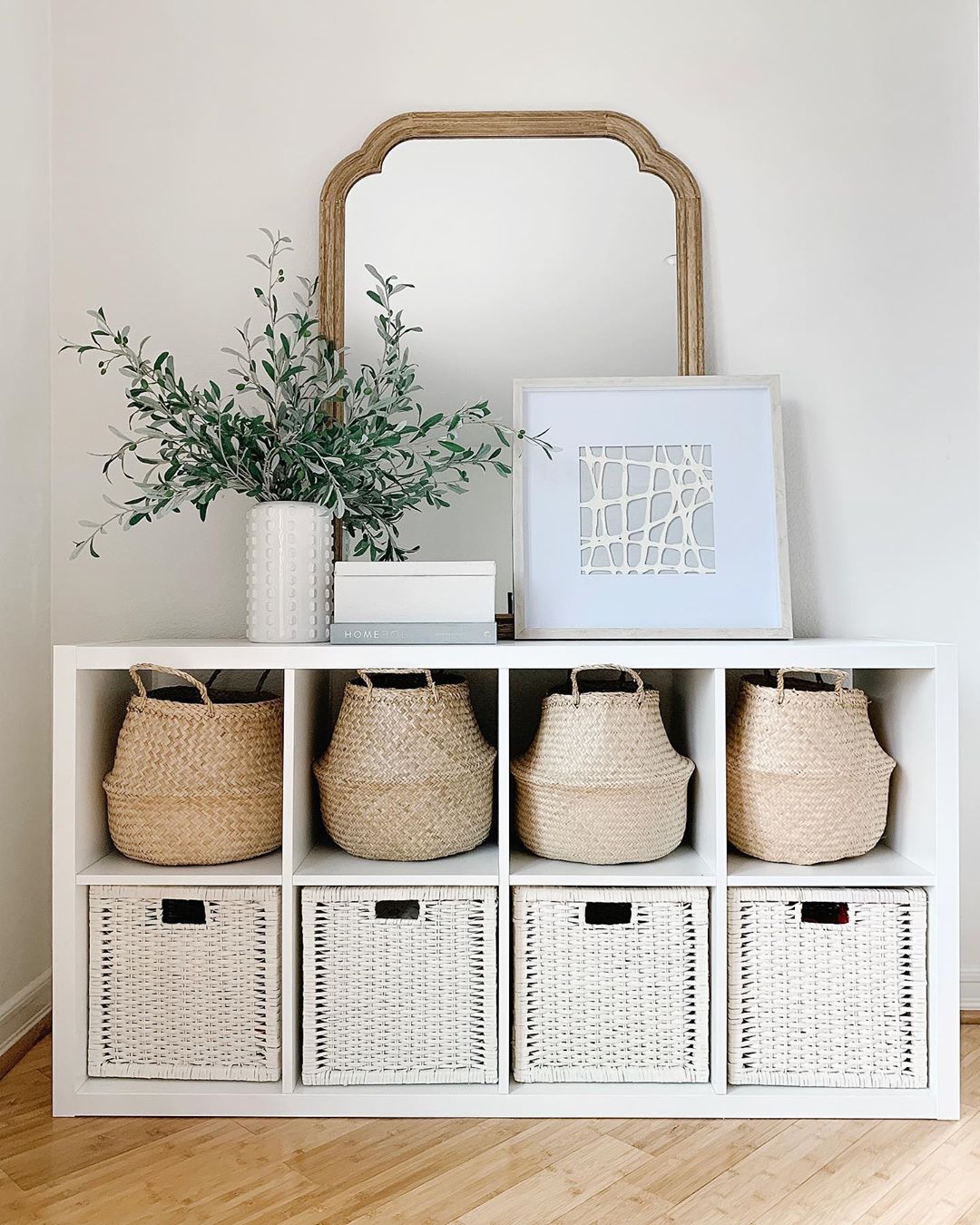 Wicker baskets on white shelf. Photo by Instagram use @simplyciani