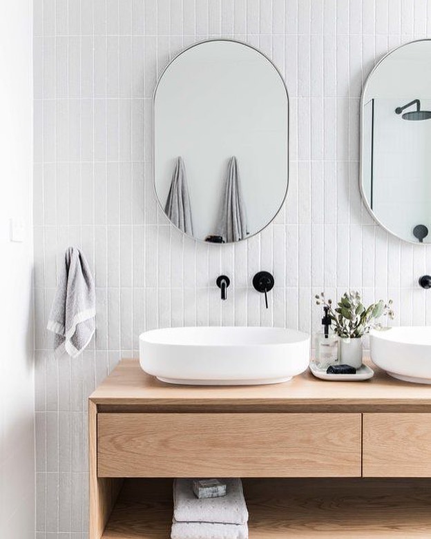 White bathroom with brown cabinets and oval mirrors. Photo by Instagram user @ribblevalleybathrooms