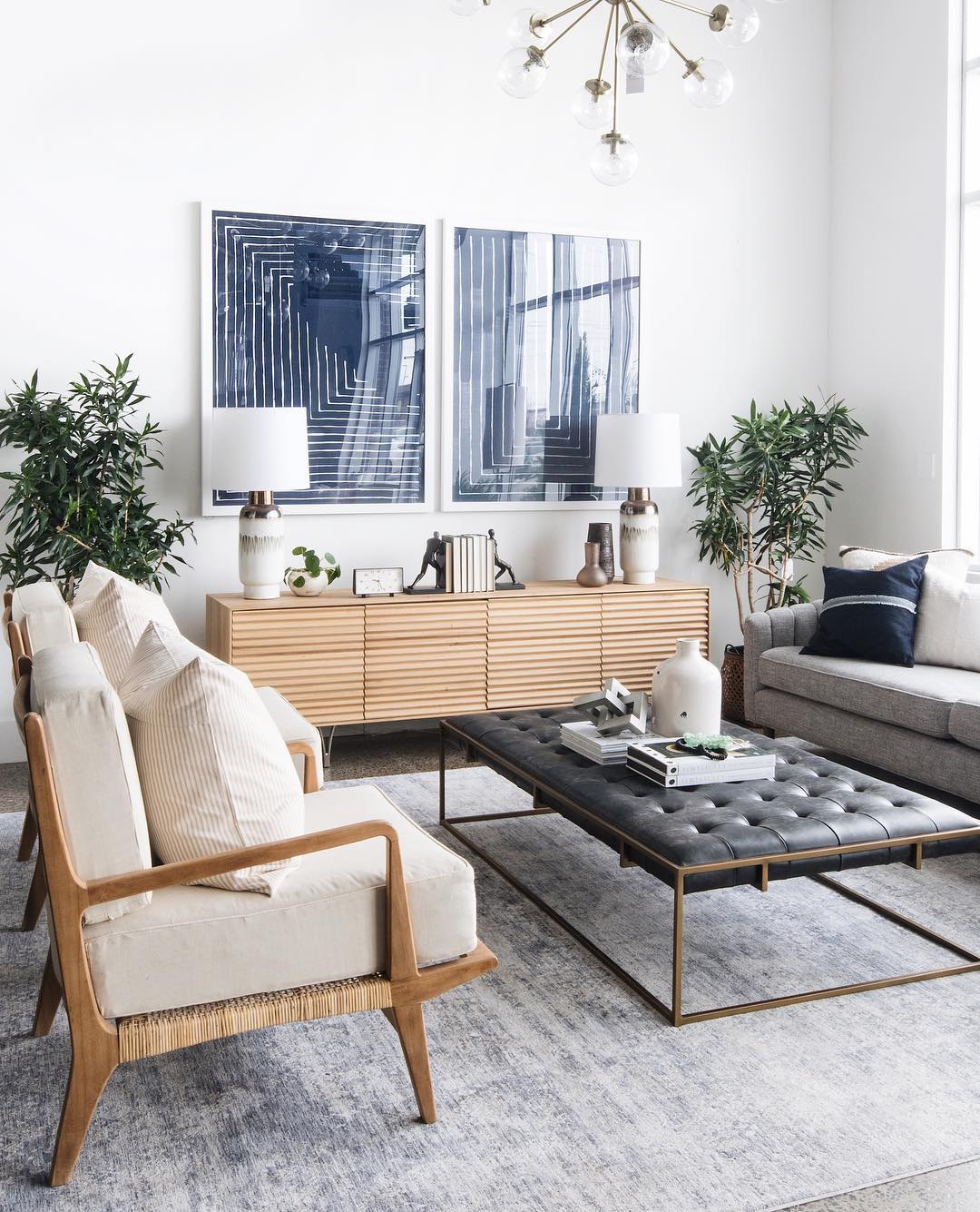 White-painted living room with blue painting on wall and white couches. Photo by Instagram user @leclairdecor