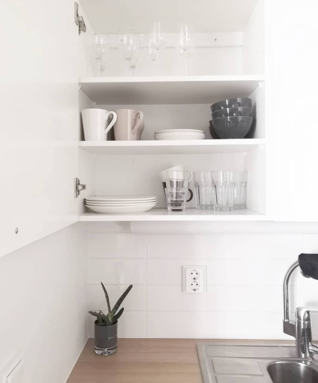 White kitchen with cabinet fulled or gray and white dishes. Photo by Instagram user @minimalismista