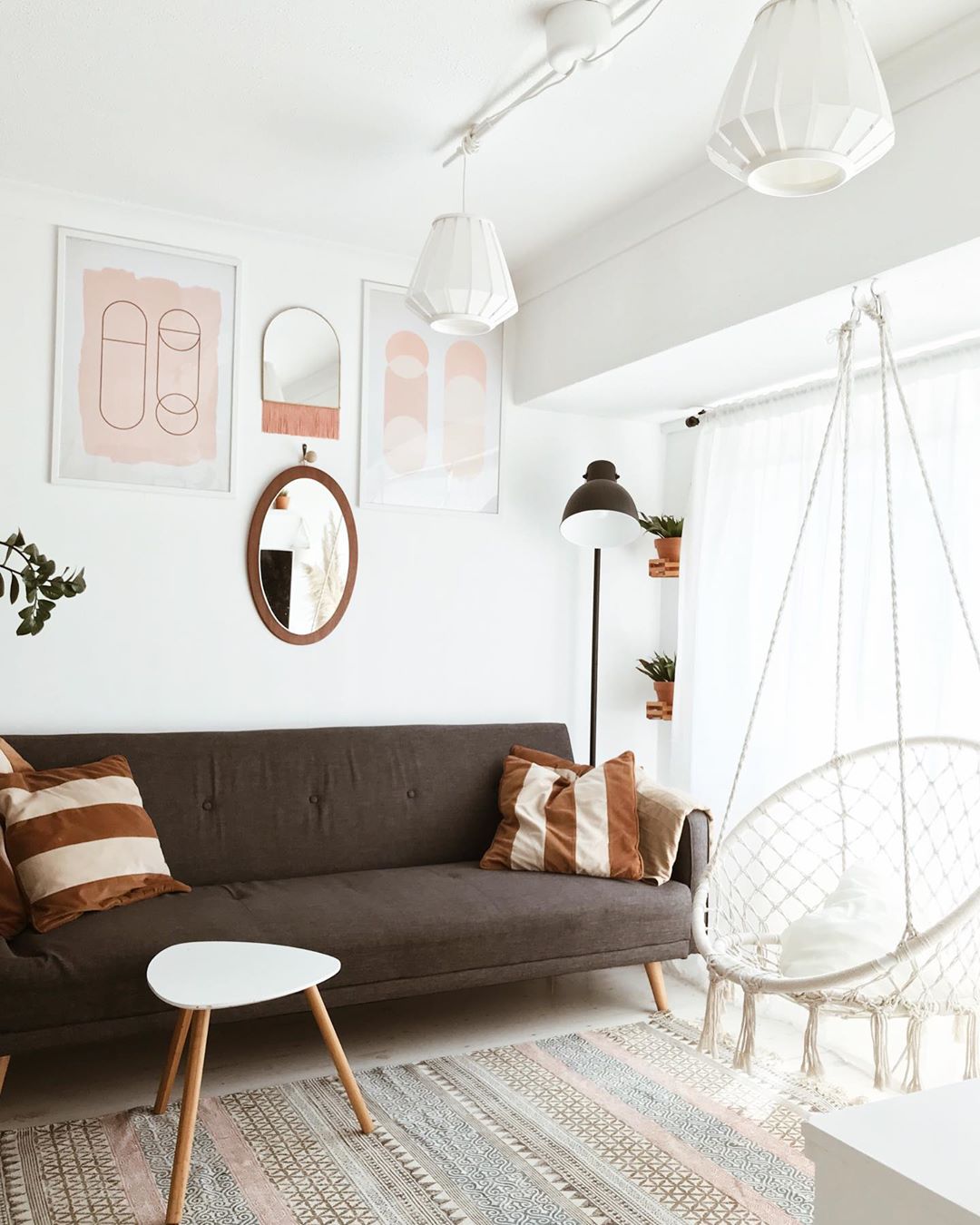White-painted living room with brown couch and white chair hanging in corner. Photo by Instagram user @mady_mom