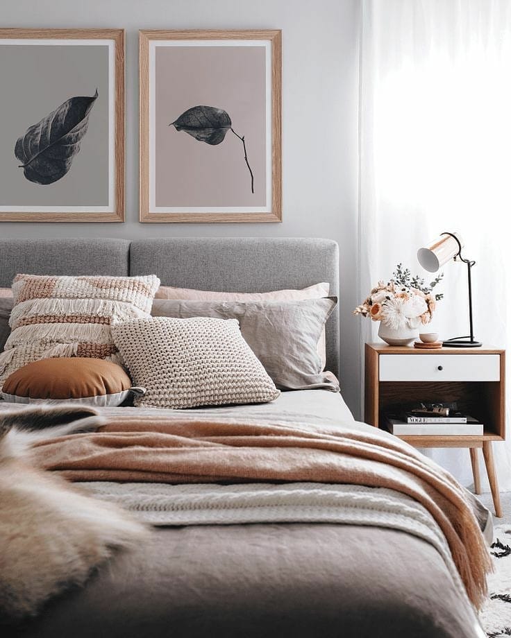 Gray bedroom with light pink pillows and leaf paintings. Photo by Instagram use @ugs_beddings