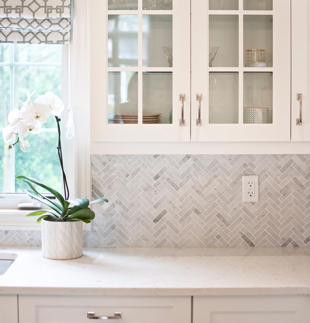 White kitchen cabinets with glass doors.Photo by Instagram user @erin_interiors