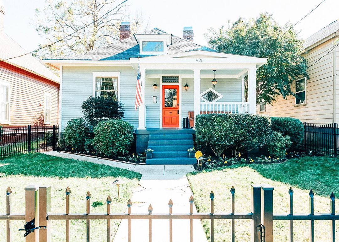 Light blue with orange front door and wrought iron fence in yard. Photo by Instagram user @chrisbillingslea