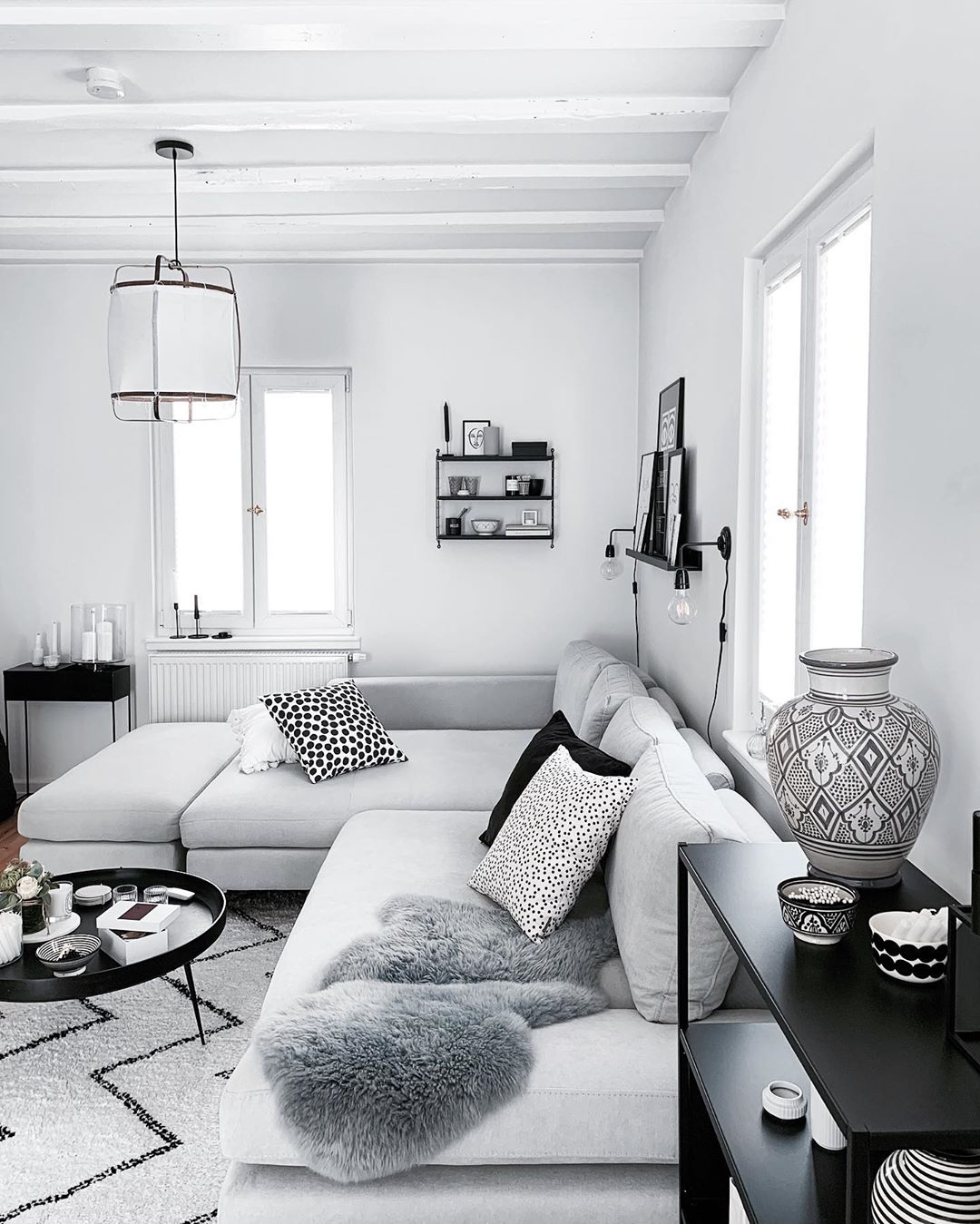 Light gray living room with gray couch and black decor. Photo by Instagram user @froehlicheszuhause