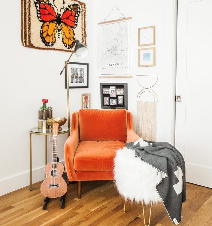 White room with orange chair and butterfly wall decor. Photo by Instagram user @bring_delight