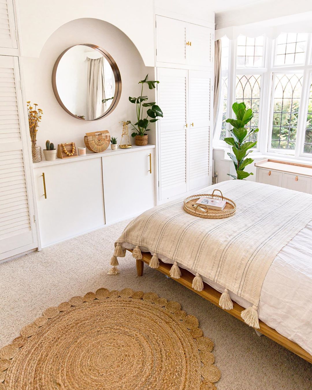 White bedroom with white bed and tan rug. Photo by Instagram user @homewithkelsey
