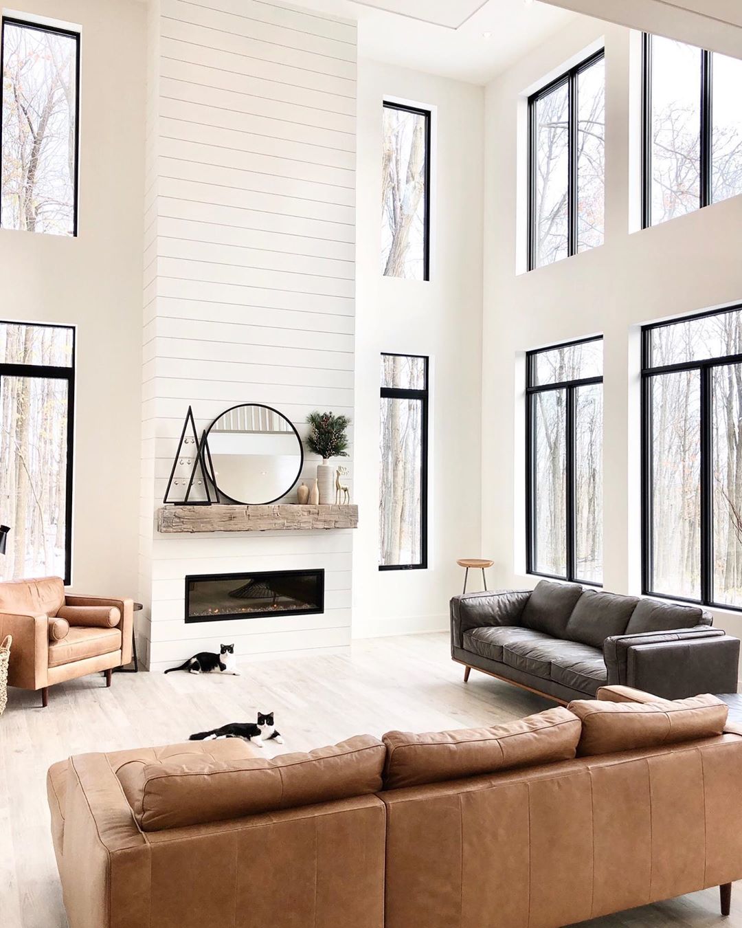 All white living room with big windows and brown couches. Photo by Instagram user @ahousewebuilt