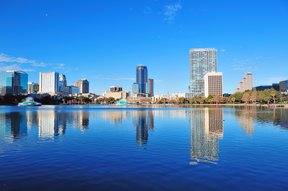 Skyline of tall buildings by water on sunny day in Downtown Orlando.