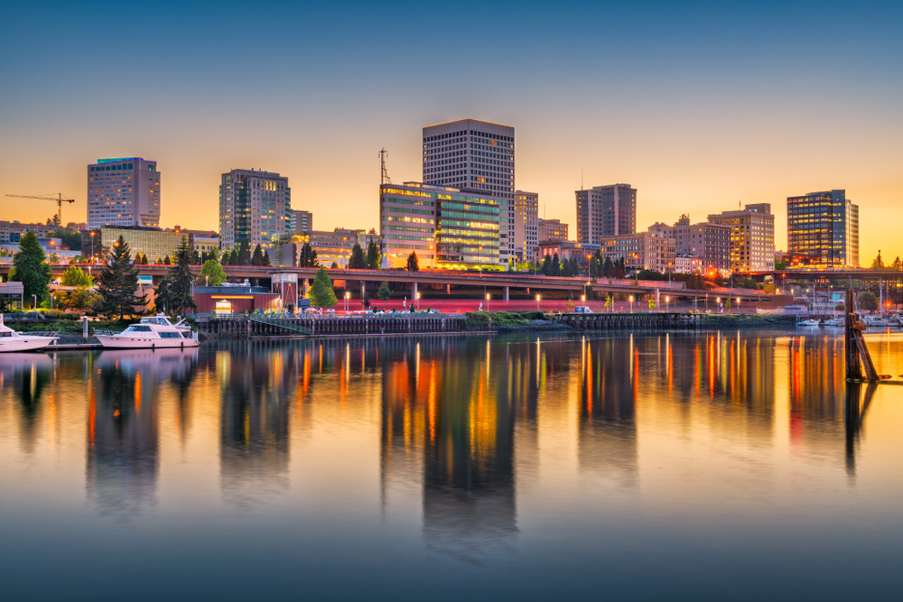 Tall buildings lit up next water at sunset in Downtown Tacoma