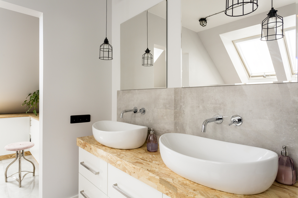 A white bathroom with dual bowl sinks on a wooden countertop