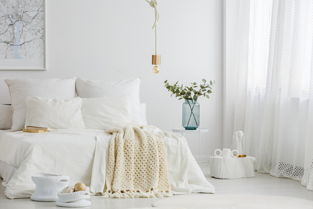 A white bedroom with white bedding and minimalist decor