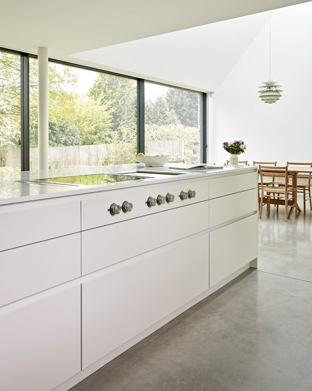 Large white kitchen with white cabinets and big windows. Photo by Instagram user @brayerdesign