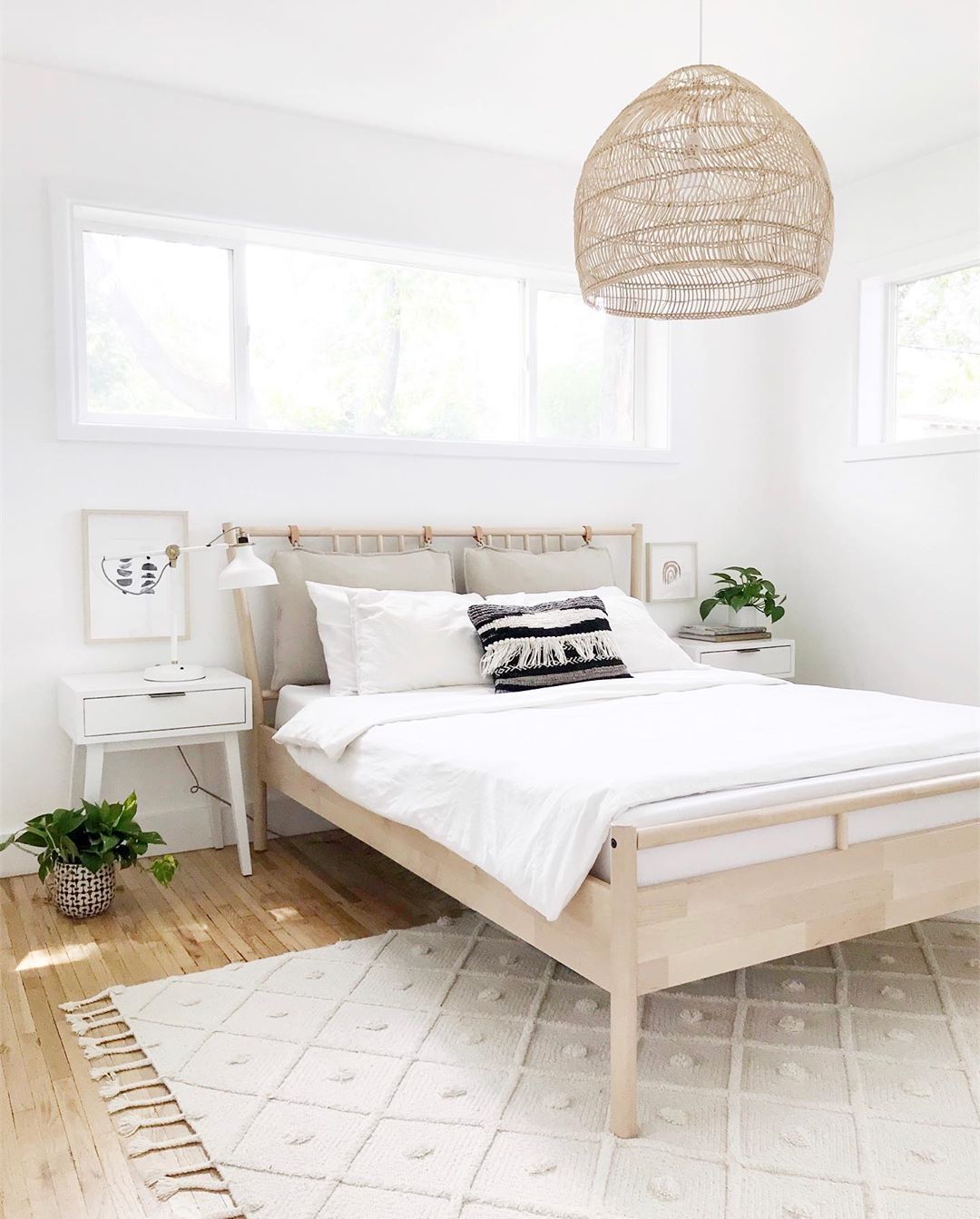 White bedroom with light brown bed and light fixture. Photo by Instagram user @farahpro