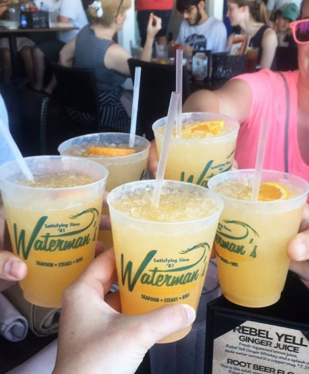 Group of people cheersing orange cocktails. Photo by Instagram user @watermanssurfsidegrille
