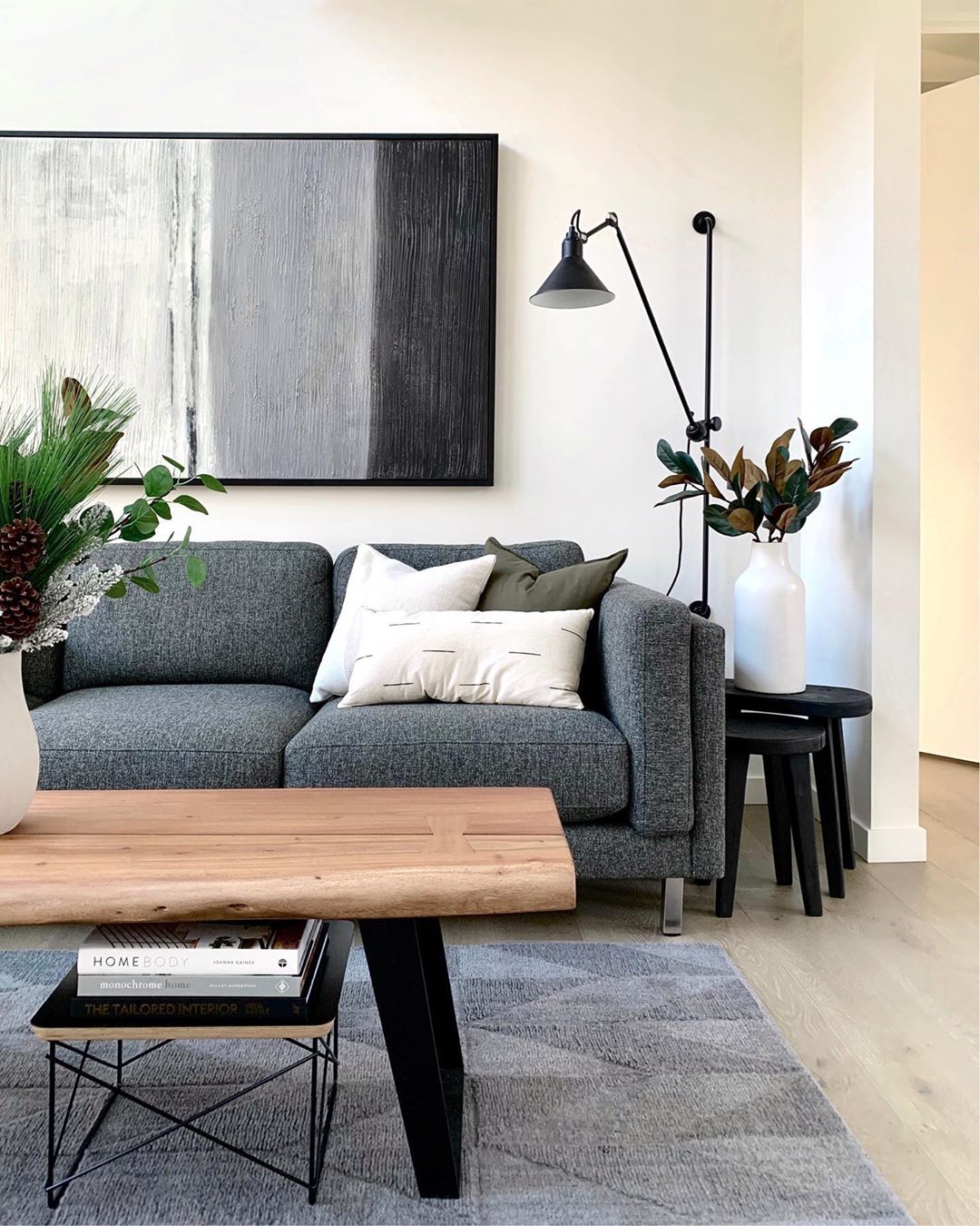 Dark gray couch and wood table in white-painted living room. Photo by Instagram user @simply.modern.living
