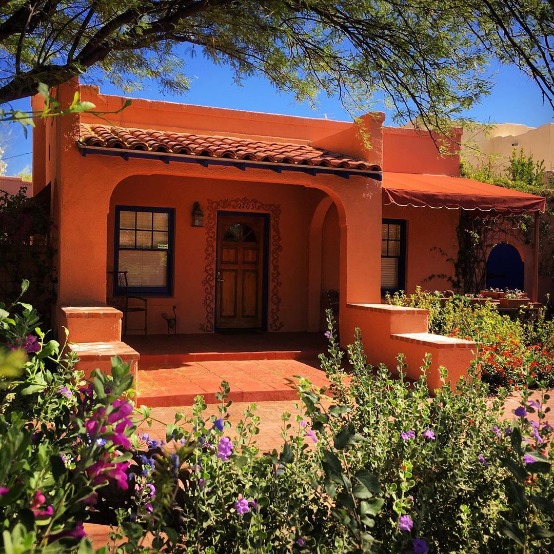 Orange house with red tole roof and plants in front yard. Photo by Instagram user @fotosimmons