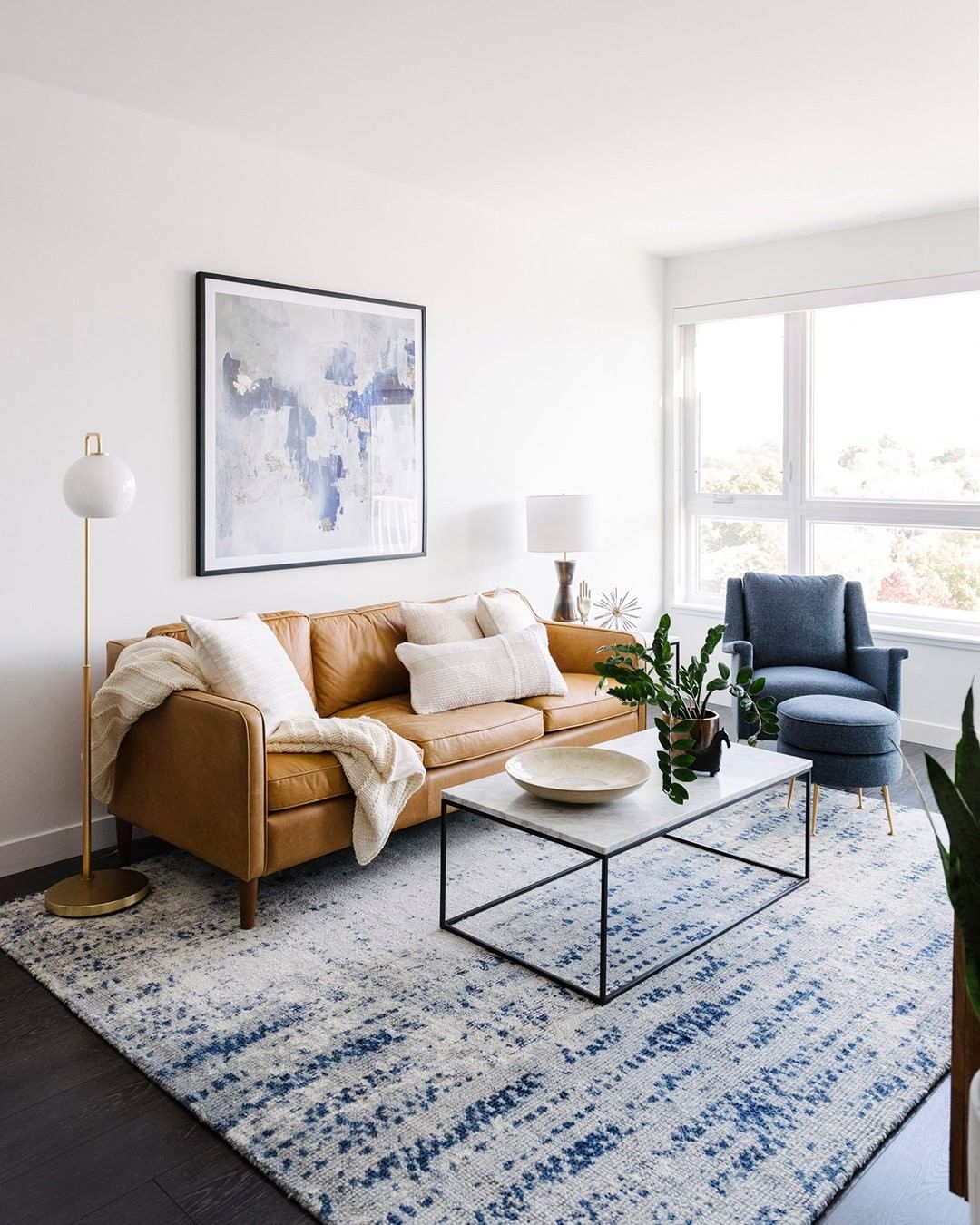White-painted living room with tan couch and blue decor. Photo by Instagram user @westelm