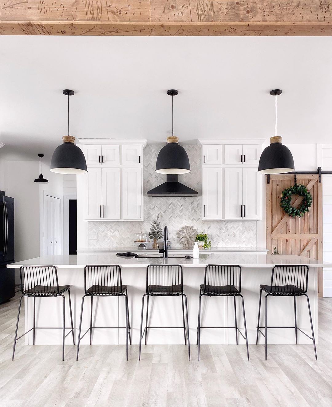 White kitchen with white cabinets and black light fixtures. Photo by Instagram user @fournorthfarmhouse