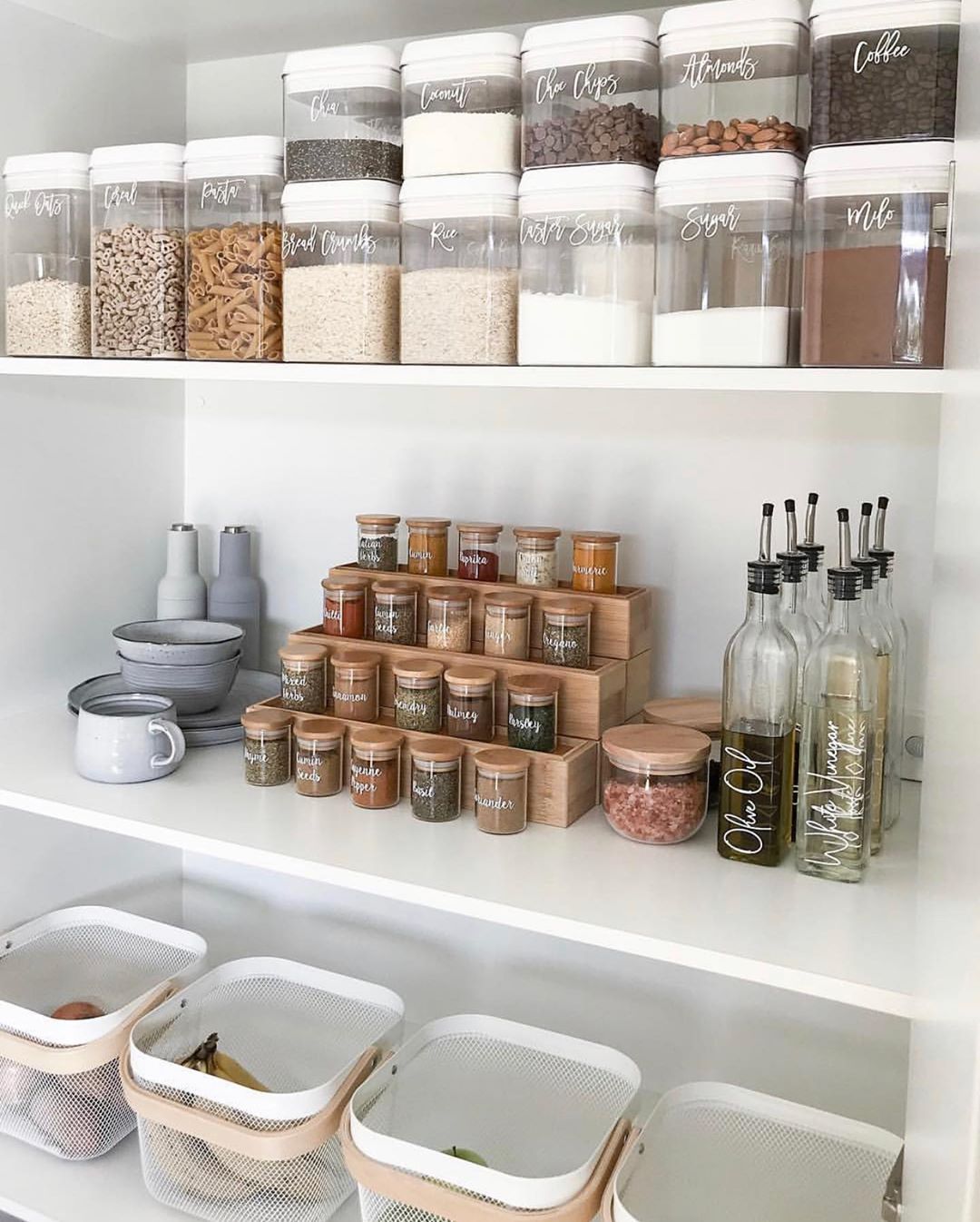 Food and spices in clear jars on white shelves. Photo by Instagram user @theruthlessorganizer
