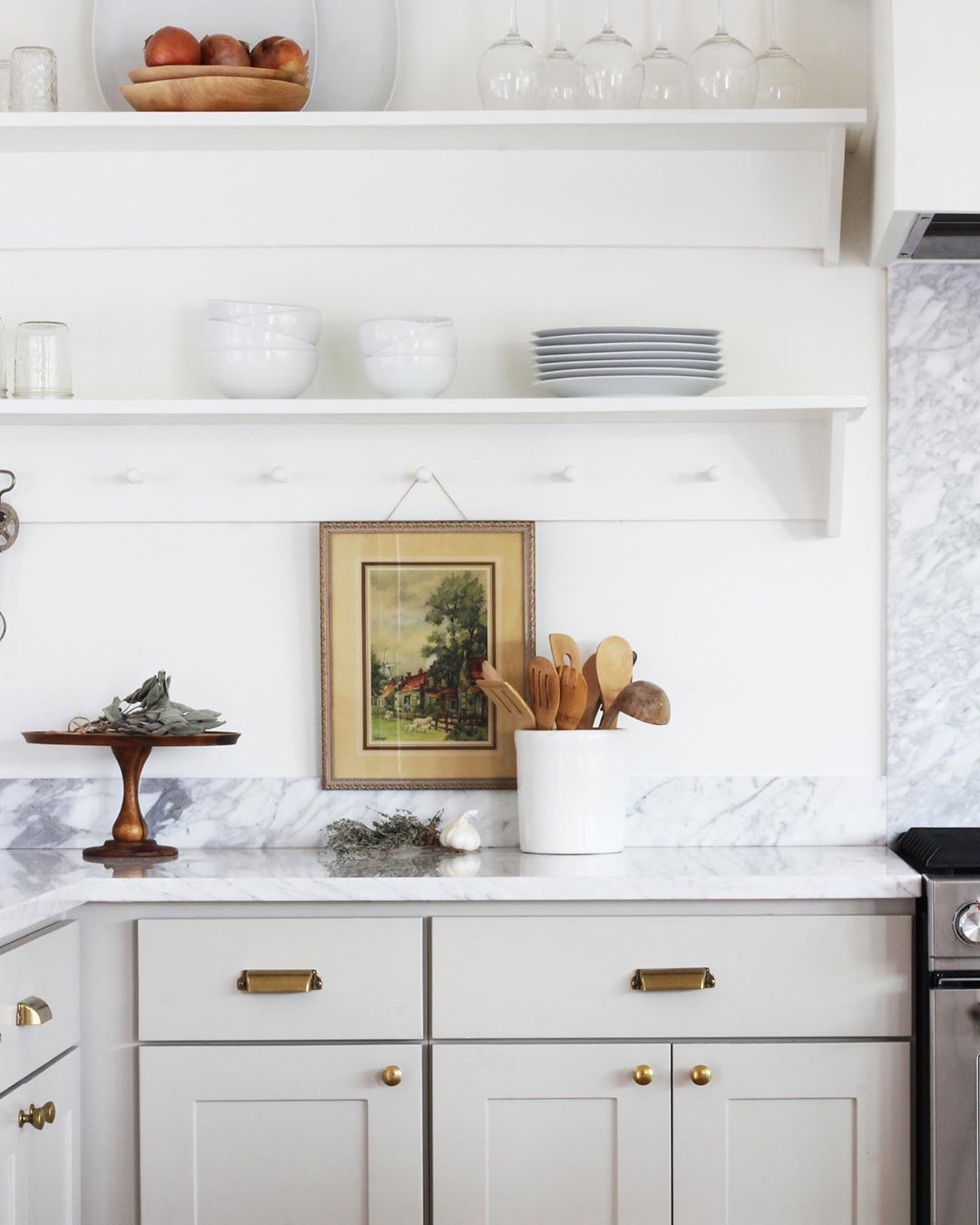Kitchen with walls and floating shelves holding white dishes. Photo by Instagram user @thegritandpolish