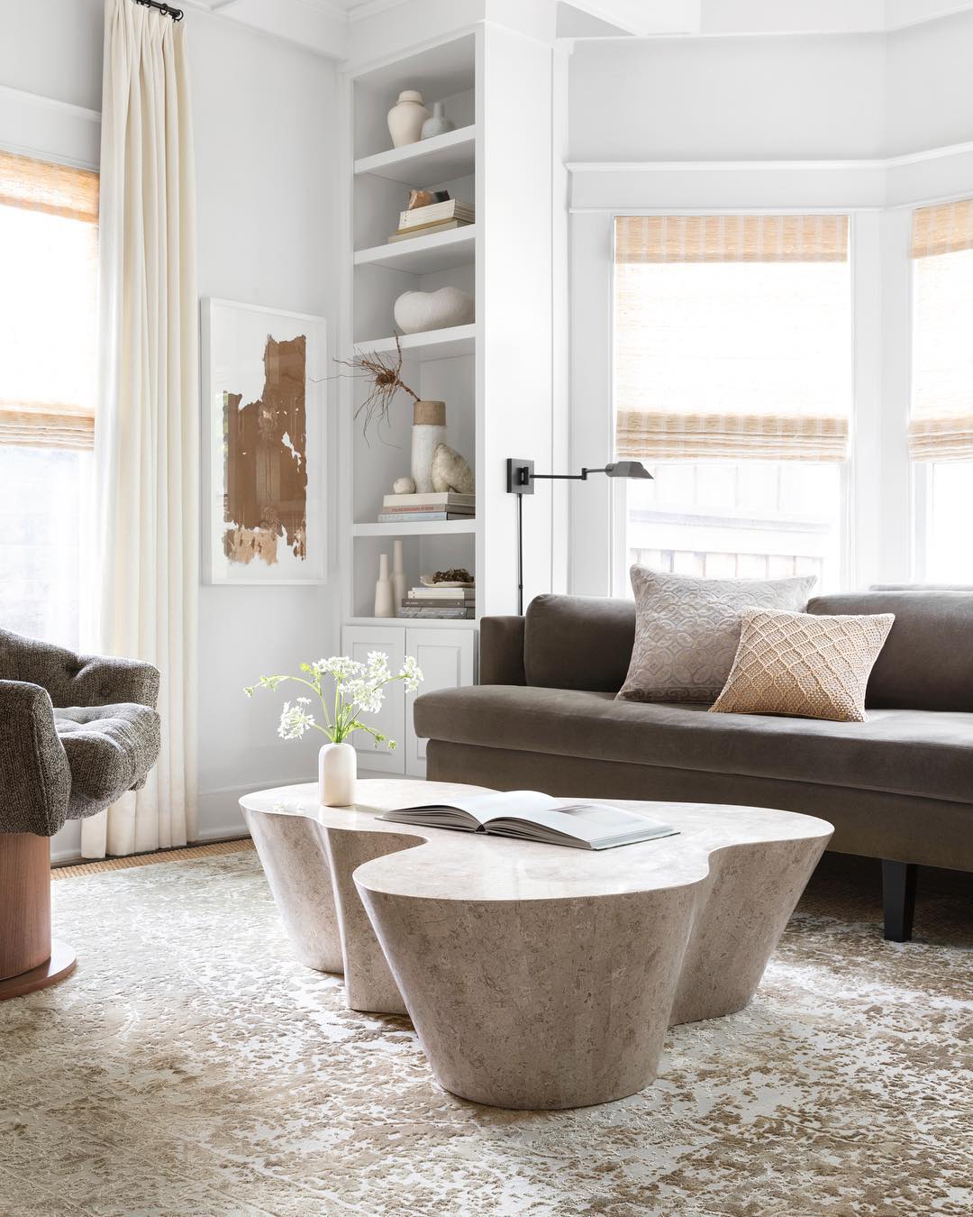 White-painted living with brown couch and concrete table. Photo by Instagram user @loloirugs