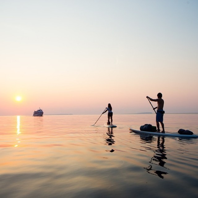 Two people paddle board at Mount Desert Island at sunset. Photo by Instagram user @terramorresort.