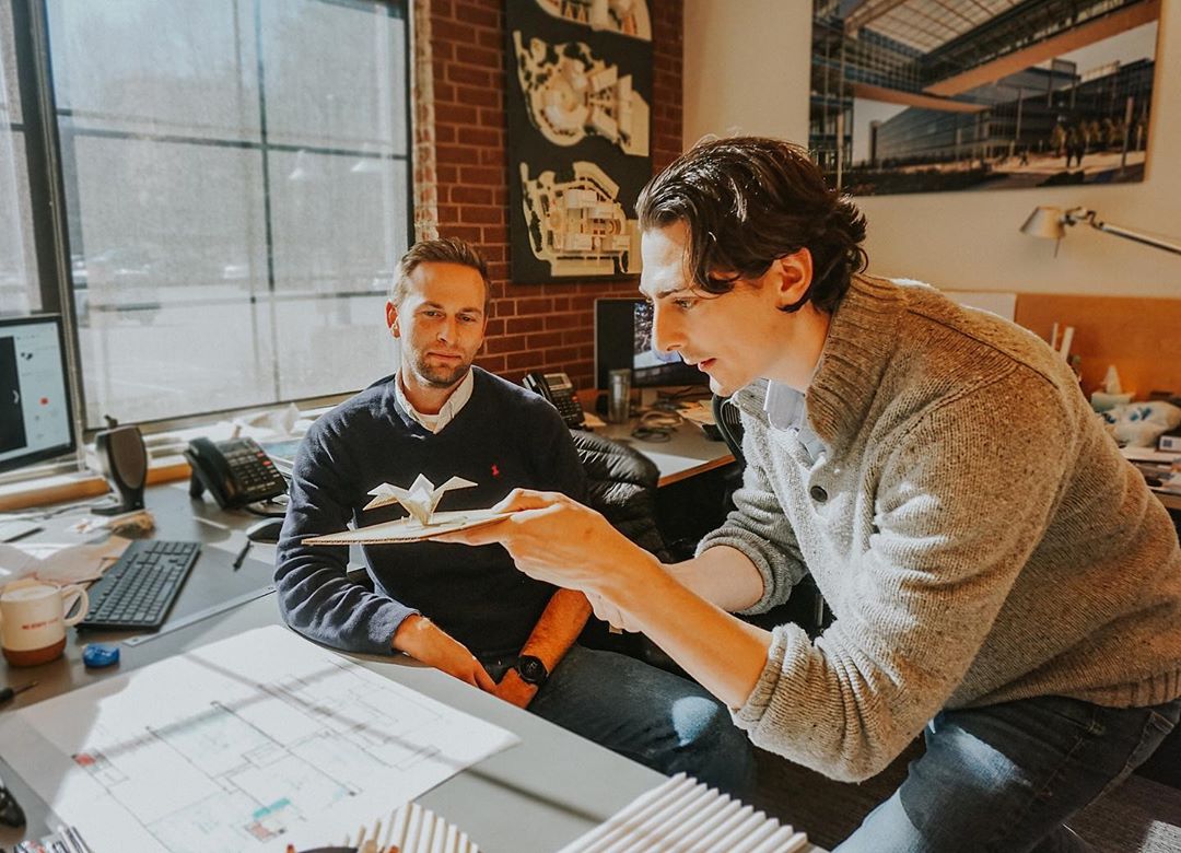 Two guys looking at paper in brick office. Photo by Instagram user @dudapaine