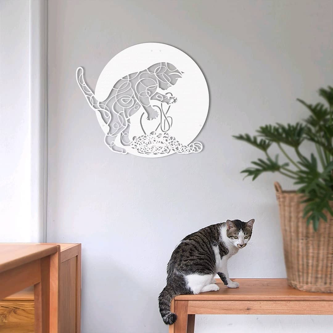 Cat sitting on table underneath picture of cat. Photo by Instagram user @artepra
