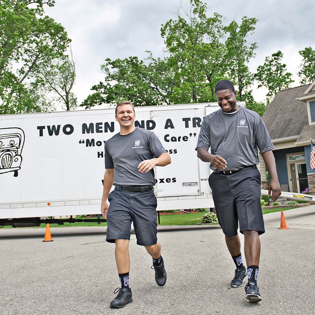 Two men walking away smiling from white truck. Photo by Instagram user @twomenandatruck