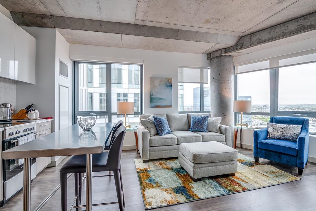 Modern apartment with gray couch and blue chair. Photo by Instagram user @compassfurnapts