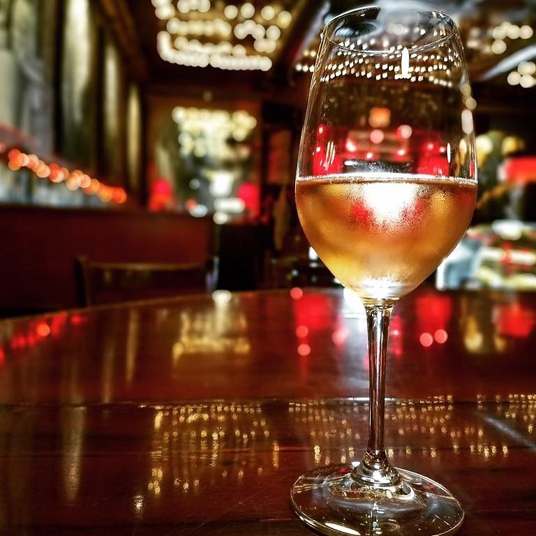 Glass of wine sitting on table at bar. Photo by Instagram user @goats2sc