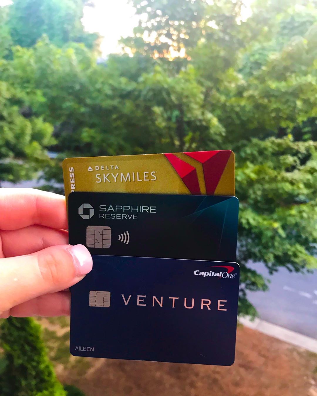 Hand holding three travel credit cards. Photo by Instagram user @teachtraveltell