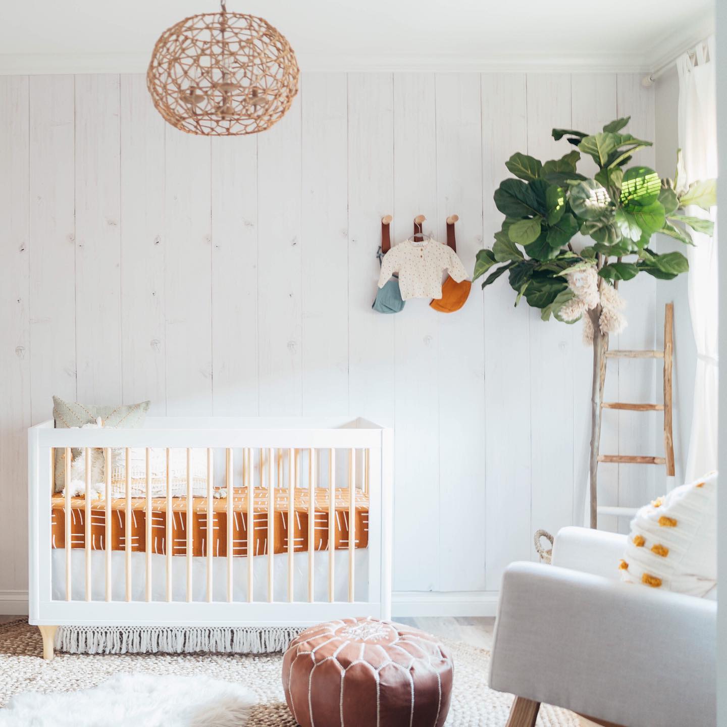 A white baby room with a crib and nursery accessories. Photo by Instagram user @readysetrico