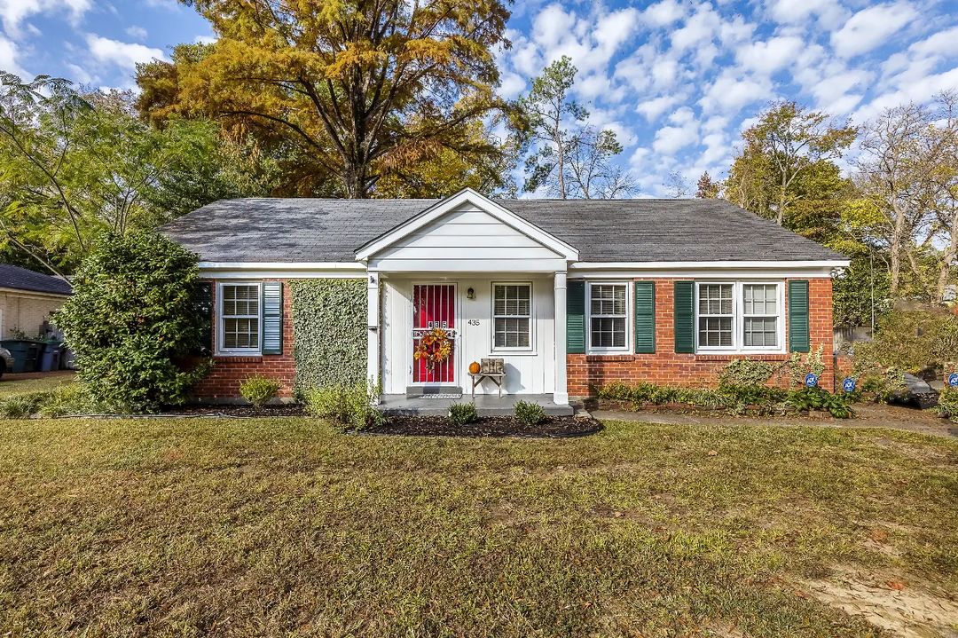 Brick traditional home with red door and large front yard in River Oaks-Kirby-Balmoral in Memphis, TN. Photo by Instagram user @hobson_realtors