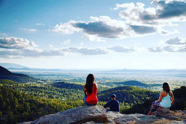 People overlooking Santa Fe landscape of forests and hills. Photo by Instagram user @cityofsantafe.