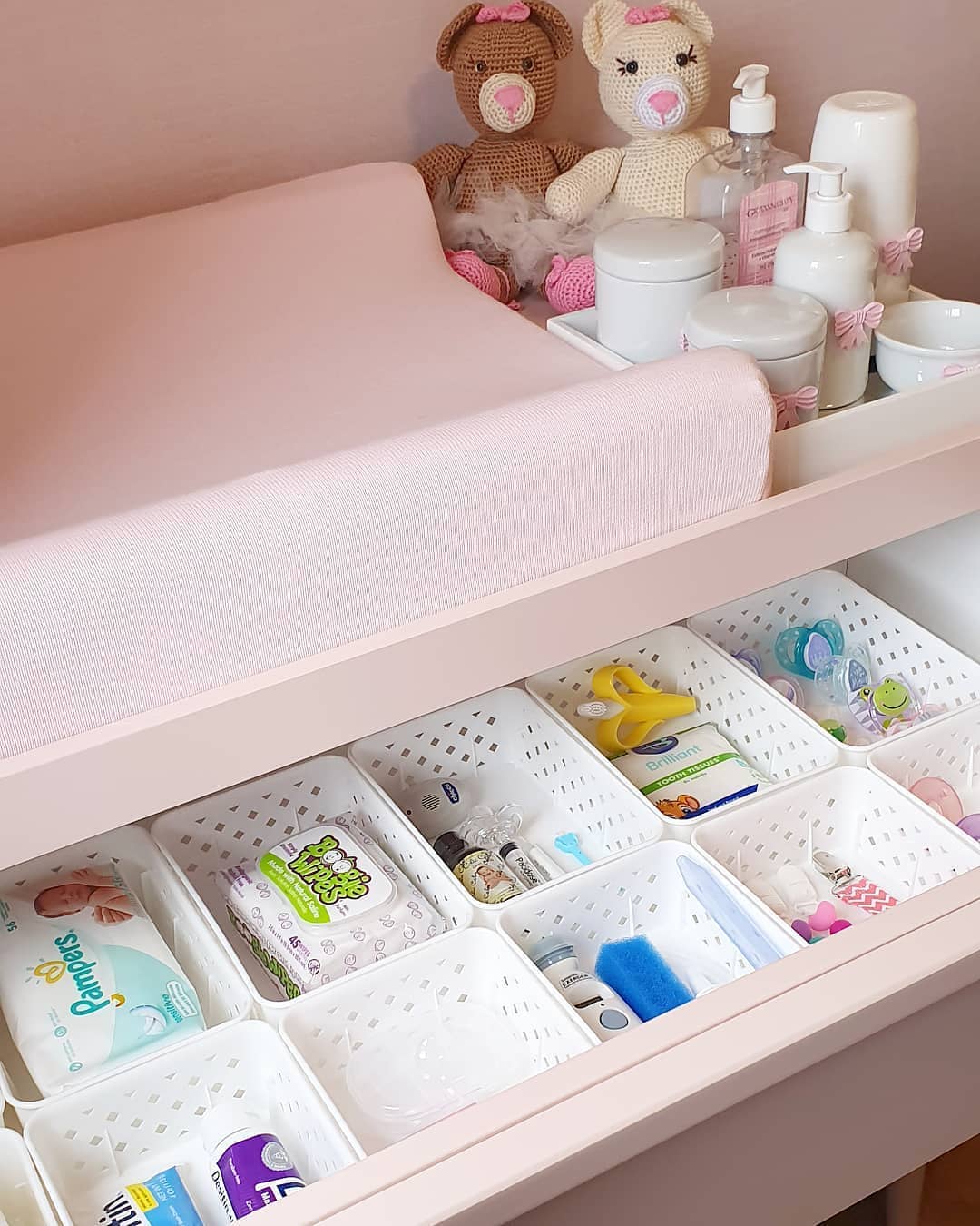 pink dresser with white plastic baskets holding small items photo by Instagram user @equilibriumservices