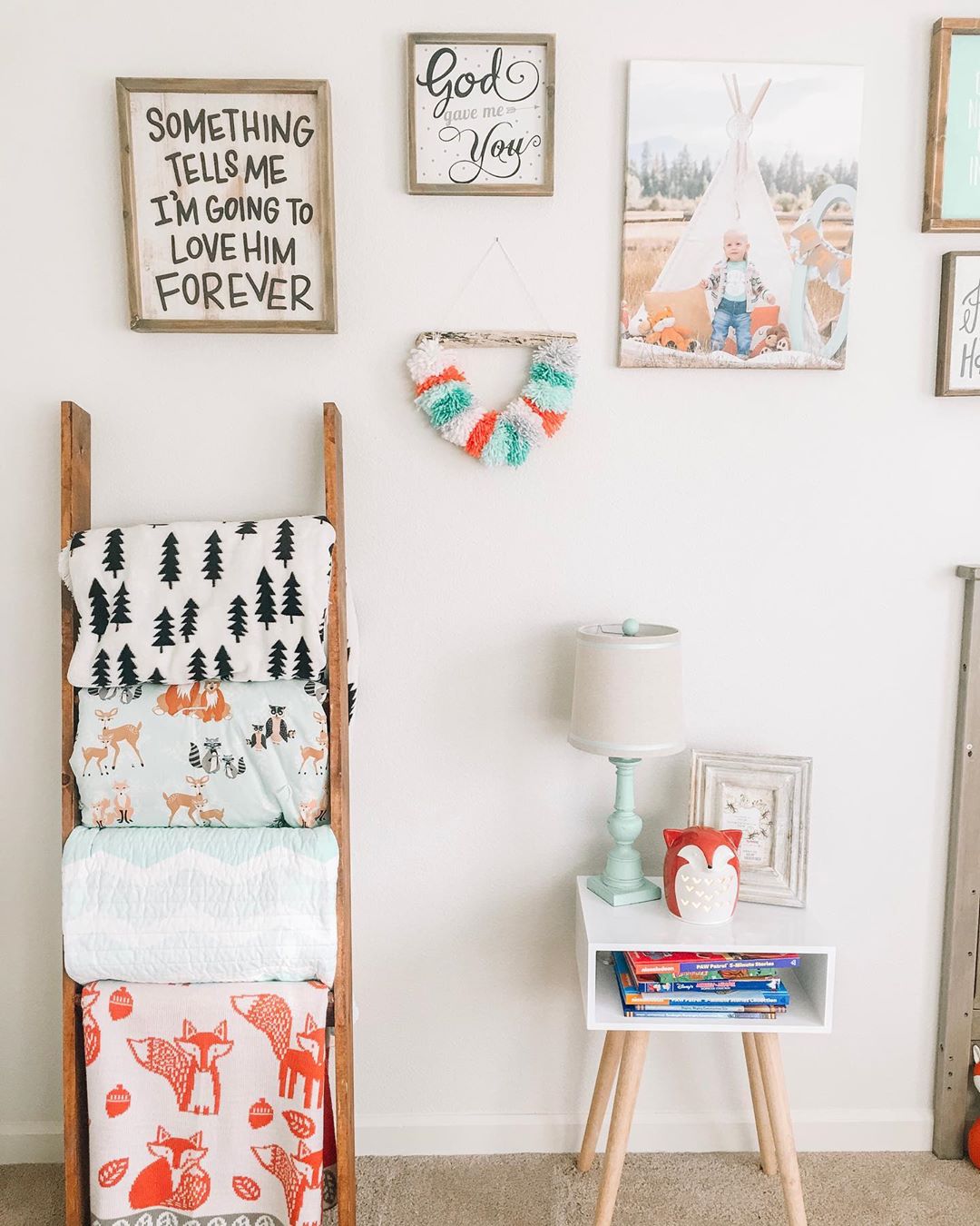 ladder with blankets stored on rungs and photos on white wall photo by Instagram user @oak.and.co