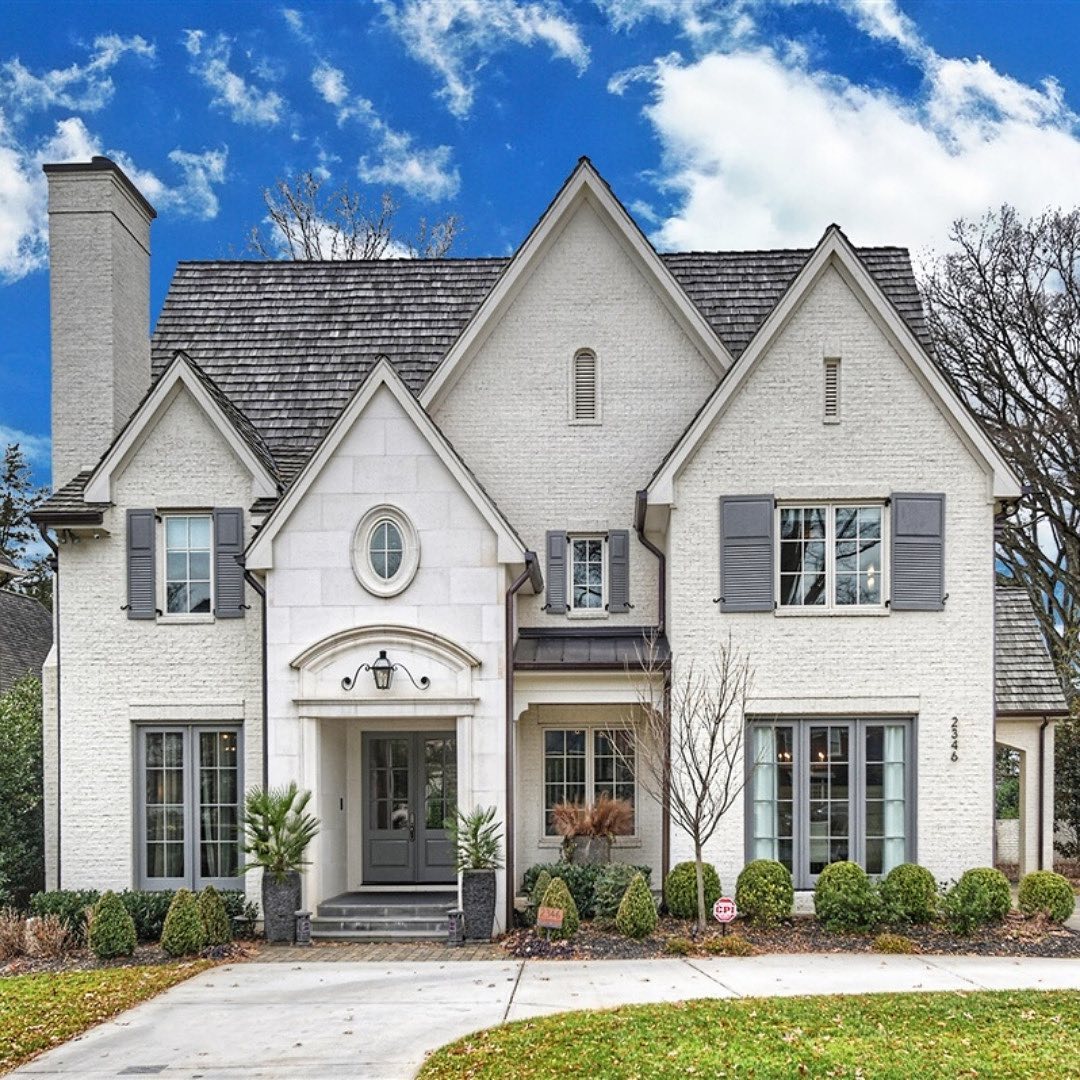 Large Cape Cod style home in Myers Park Charlotte with white brick and gray accents. Photo by Instagram user @ivesterjacksonchristies