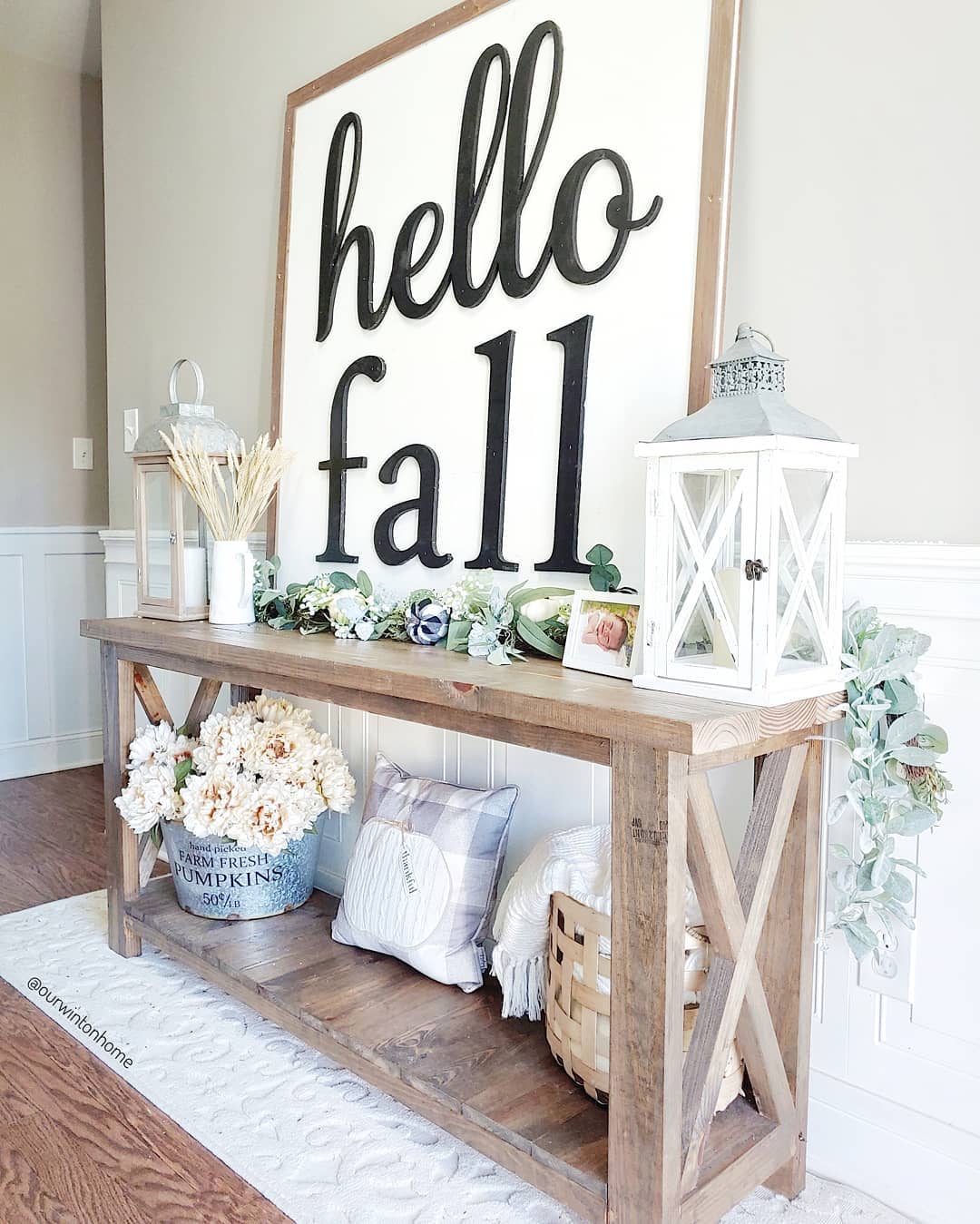 White sign on wood table in entryway.