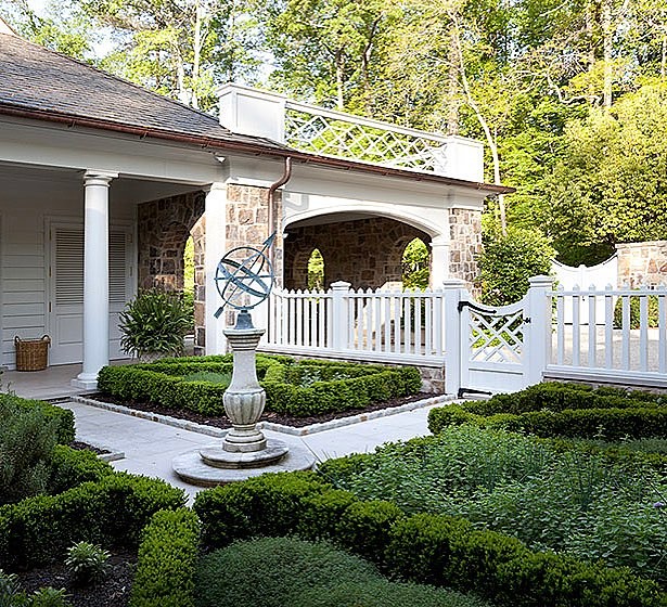 backyard landscaping with sun dial and white fence surrounding short shrubs photo by Instagram user @johnbaranellodesign