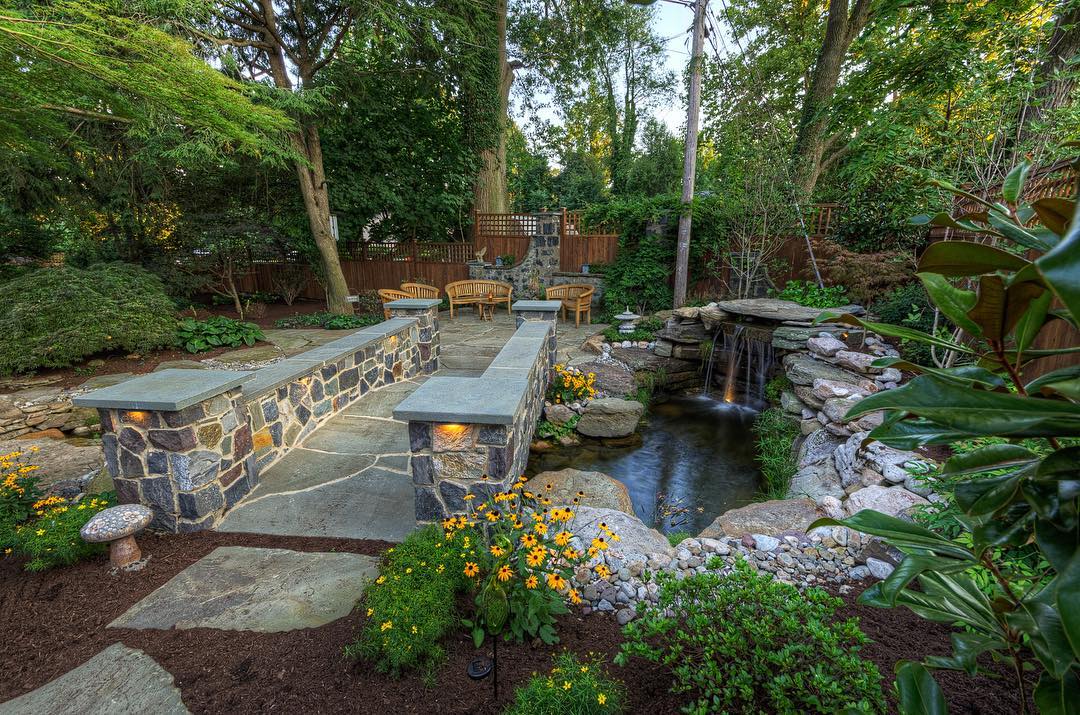 backyard landscaping with nice, straight lines and water feature and bridge photo by Instagram user @disablandscaping