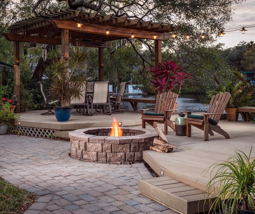 backyard patio area with firepit and pergola with seating all around photo by Instagram user @jjmaterials