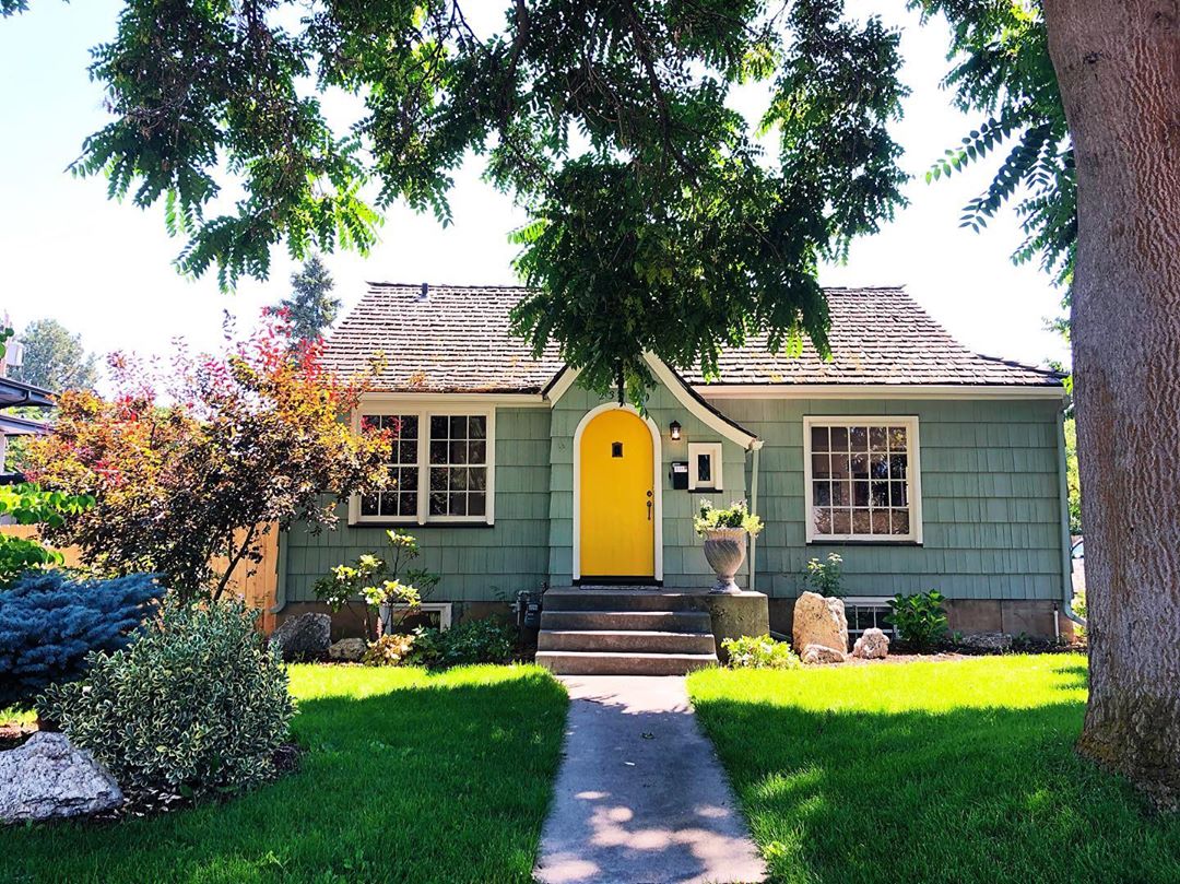 green home with yellow door with large tree in front yard photo by Instagram user @jessicadoss