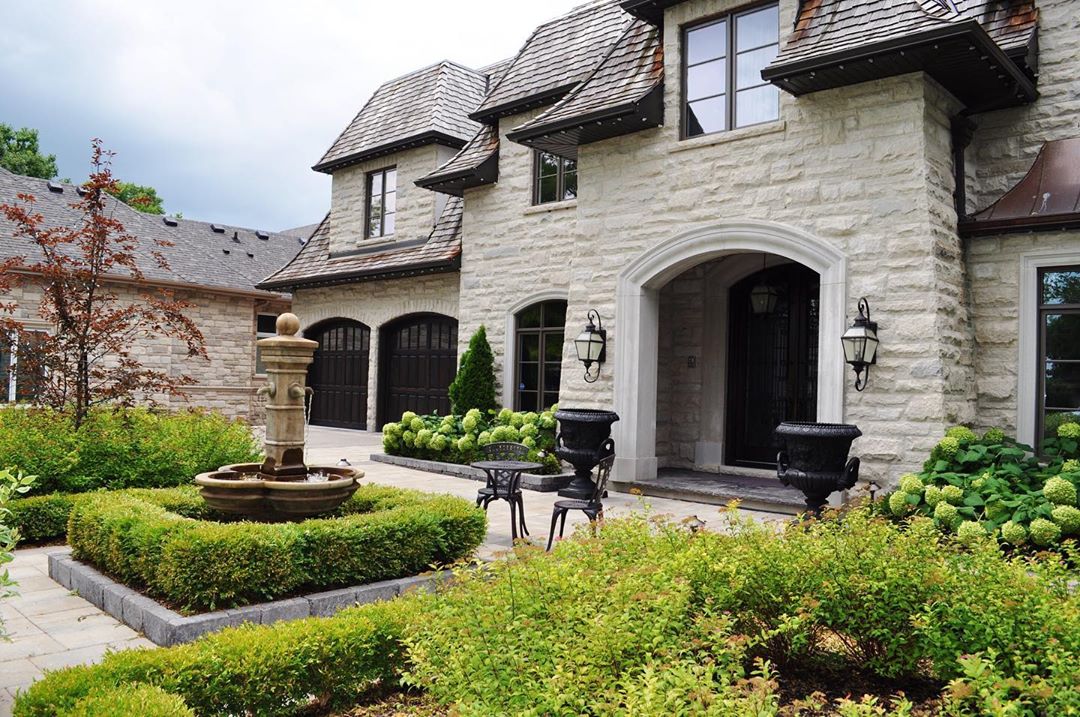 nice stone home with large backyard with a water feature in the center photo by Instagram user @mvklandscapedesign