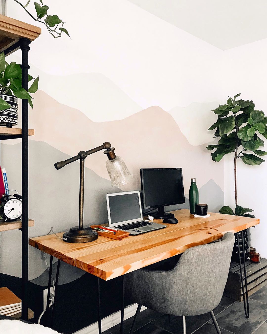 Home office with wood top desk and iron legs and small gray chair and plants photo by Instagram user @thekiwihome
