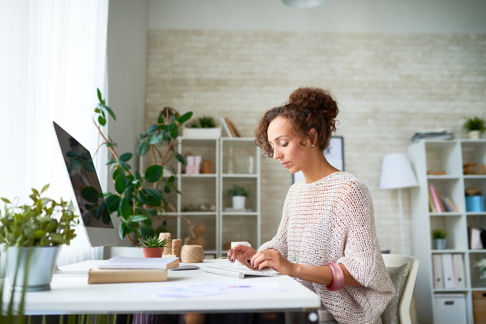 A women sitting at her desk with a computer typing on a keyboard