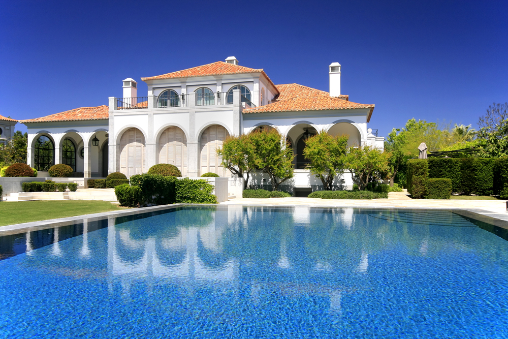 large mansion with big blue pool and perfect landscaping surrounding