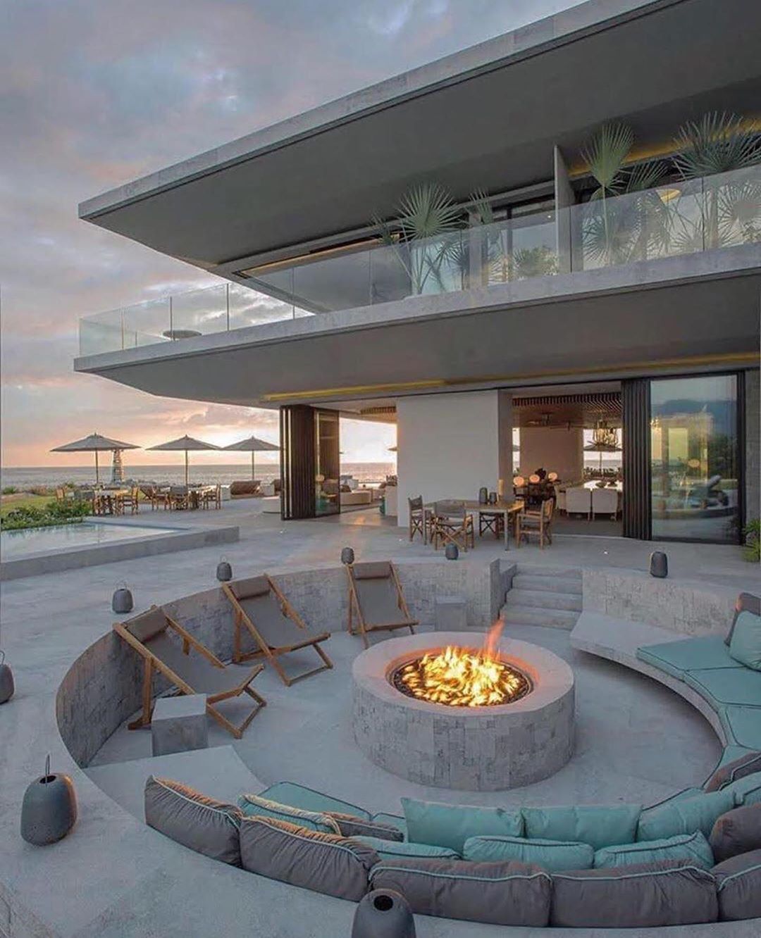 large outdoor sunken patio with fire pit and half moon couch photo by Instagram user @beautyofhouses